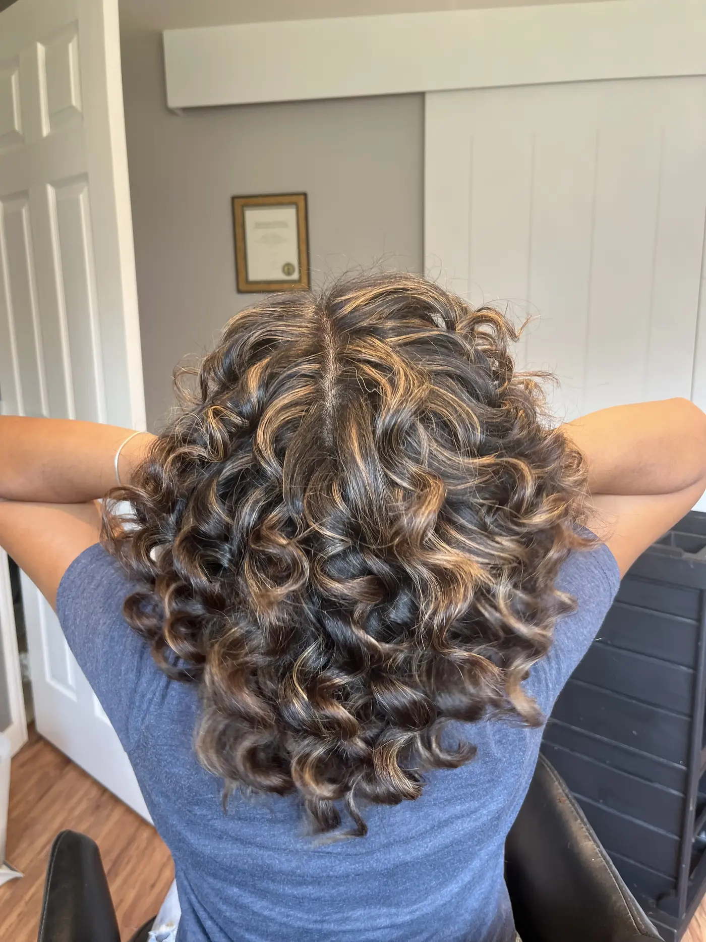 Back view of defined curls with warm caramel highlights at Zobeida's salon in Kelowna